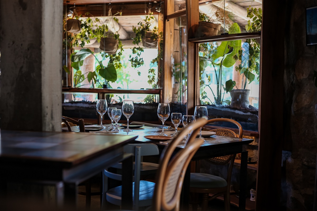 Interior de restaurante rústico de Mar del Plata con mesas de madera y vino