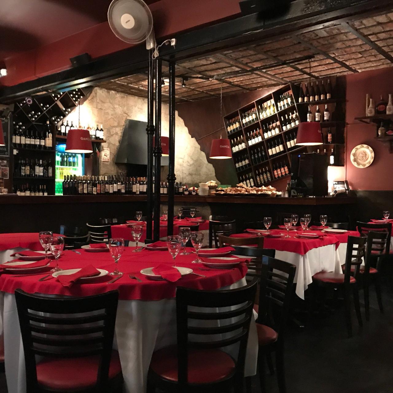 Interior de bodegón italiano en Mar del Plata con manteles rojos y horno de piedra