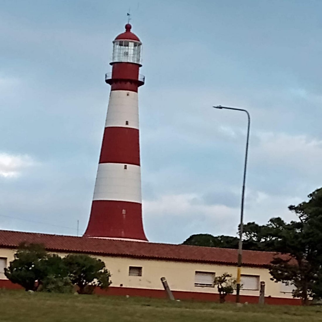 Faro de Punta Mogotes con franjas rojas y blancas y chalet amarillo