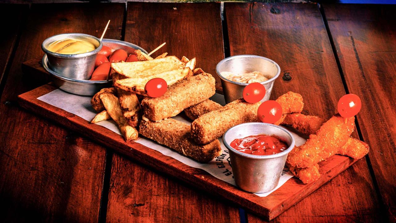 Picada con snacks fritos croquetas y salsas en tabla de madera