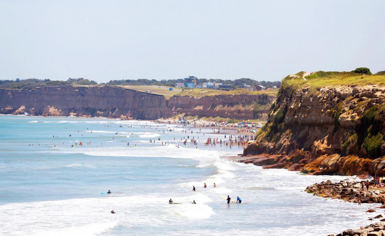 Playa Las Toscas de Mar del Plata con surfistas, bañistas y acantilados al fondo
