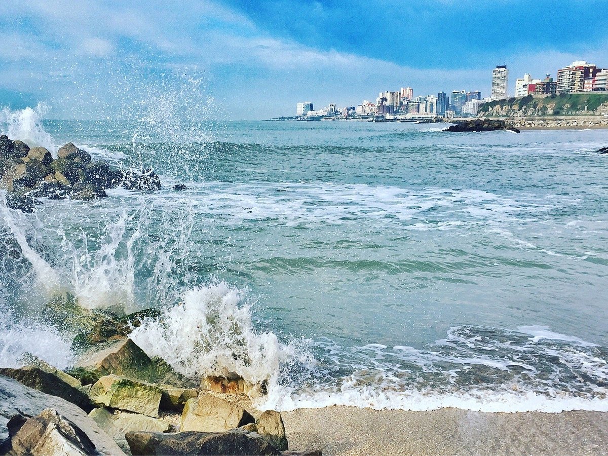 Escollera y rompeolas de Mar del Plata con olas y ciudad al fondo