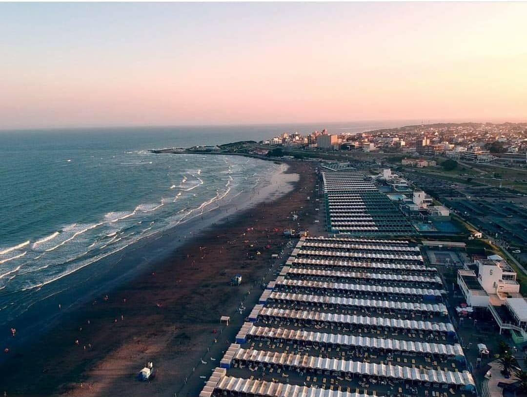 Playa Mogotes de Mar del Plata al atardecer con carpas y mar tranquilo