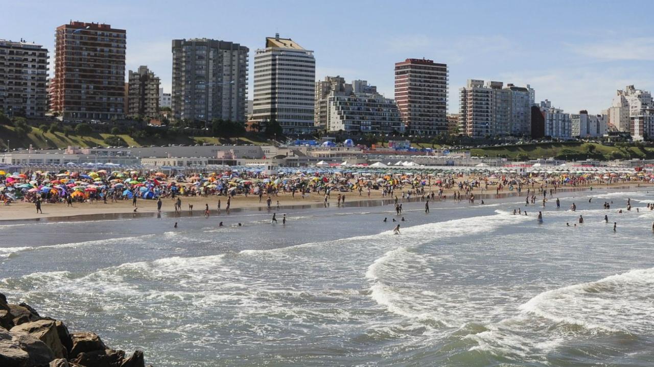 Playa Las Toscas de Mar del Plata con sombrillas, bañistas y edificios al fondo