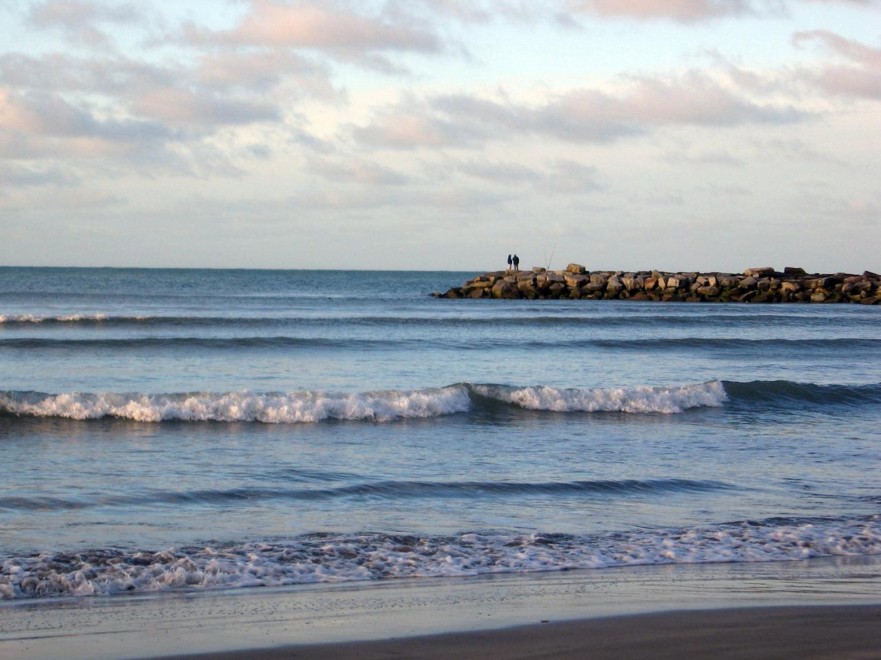 Atardecer en la Playa Las Toscas de Mar del Plata con rompeolas y figuras